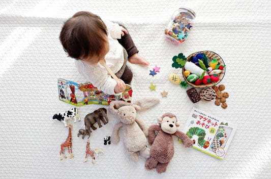 Niño con varios juguetes sobre la cama - Imagen nota desarrollo psicomotor del niño