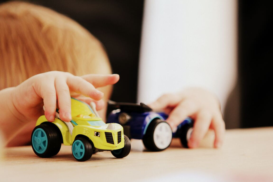 Niño jugando con dos autos de juguetes - imagen de nota de blog habilidades que se desarrollan en el juego